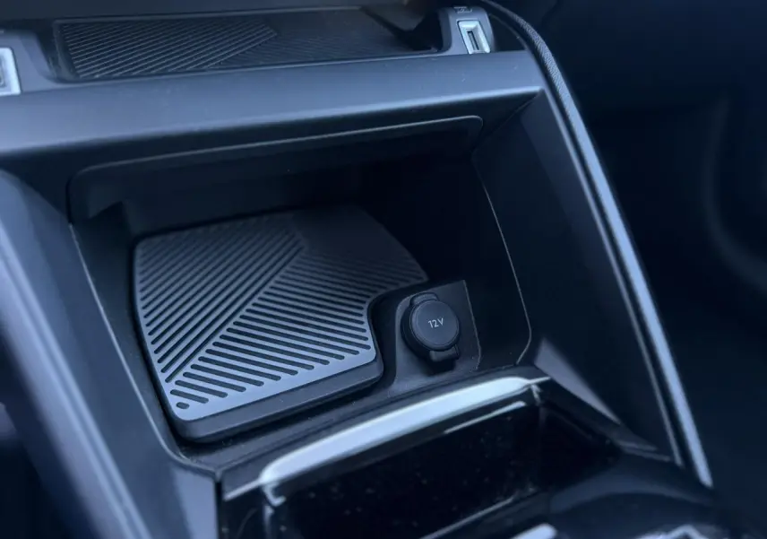 Détail de la console centrale intérieure de la Citroën C4 Hybrid 2025, prise en plongée montrant la prise 12V et un espace de rangement noir.