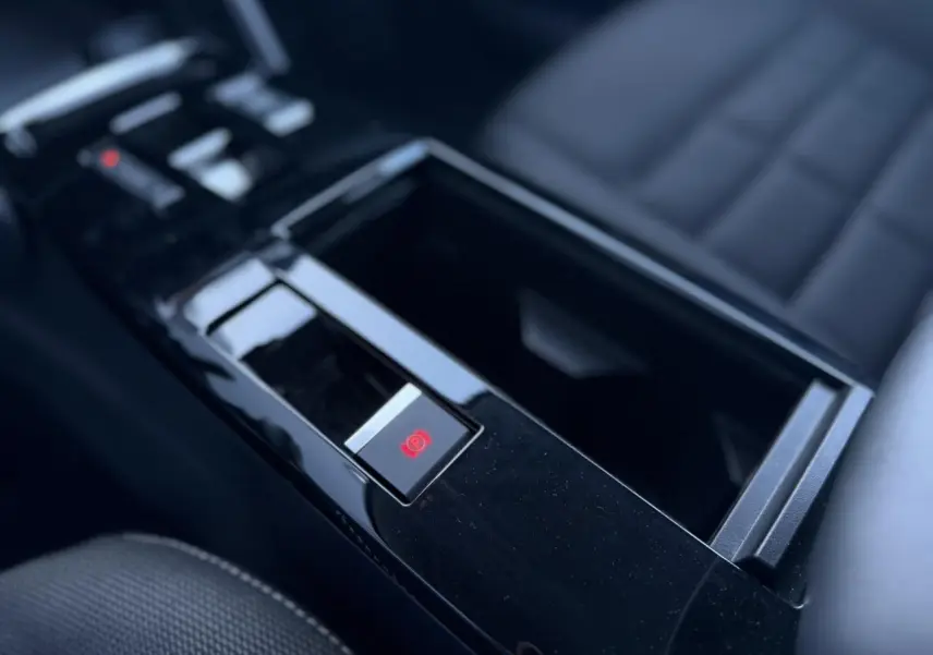 Gros plan sur la console centrale noire brillante avec frein de stationnement électrique de la Citroën C4 Hybrid 2025.