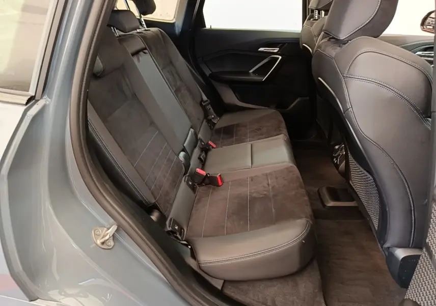 Vue intérieure arrière gauche montrant la banquette 3 places en cuir et alcantara du BMW X1 xDrive25e gris foncé 2023.
