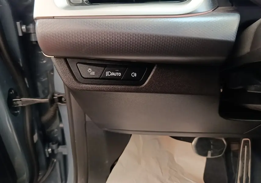 Détail des commandes d’éclairage sur le côté gauche du tableau de bord d’un BMW X1 gris foncé 2023.