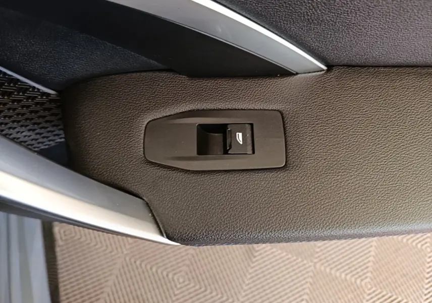 Détail du bouton de commande de vitre sur la garniture intérieure côté conducteur d’un BMW X1 gris foncé 2023.