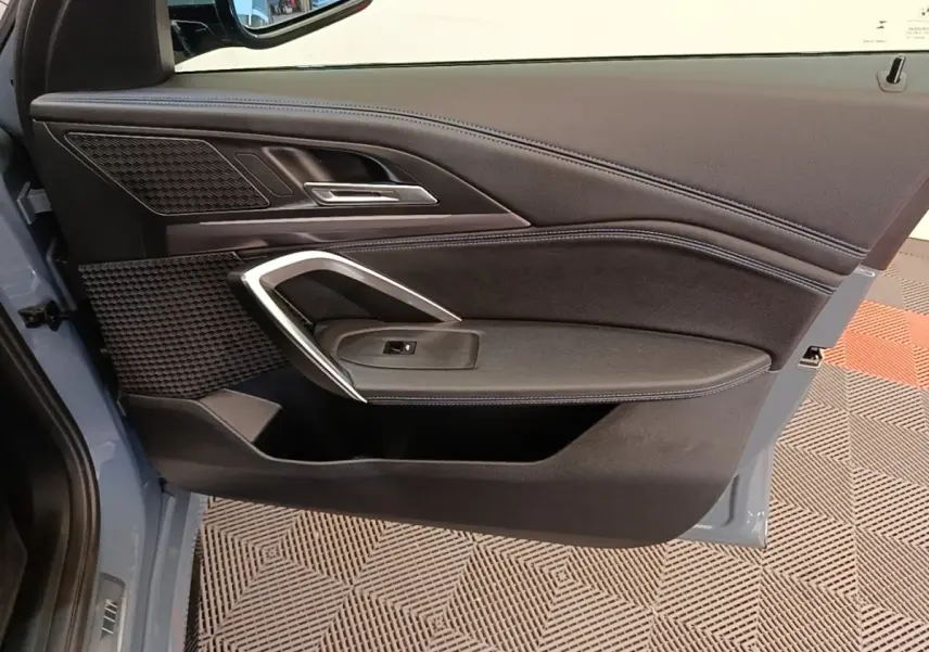 Vue intérieure de la porte avant gauche d’un BMW X1 xDrive25e M Sport 2023, garniture noire avec insert alu.