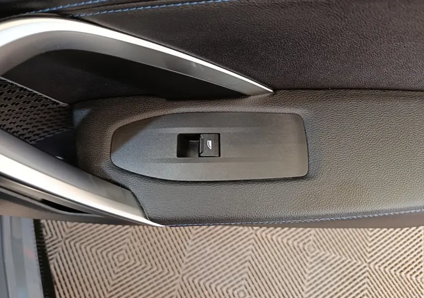Bouton de commande de lève-vitre sur la porte intérieure côté conducteur d'une BMW X1 gris foncé 2023.