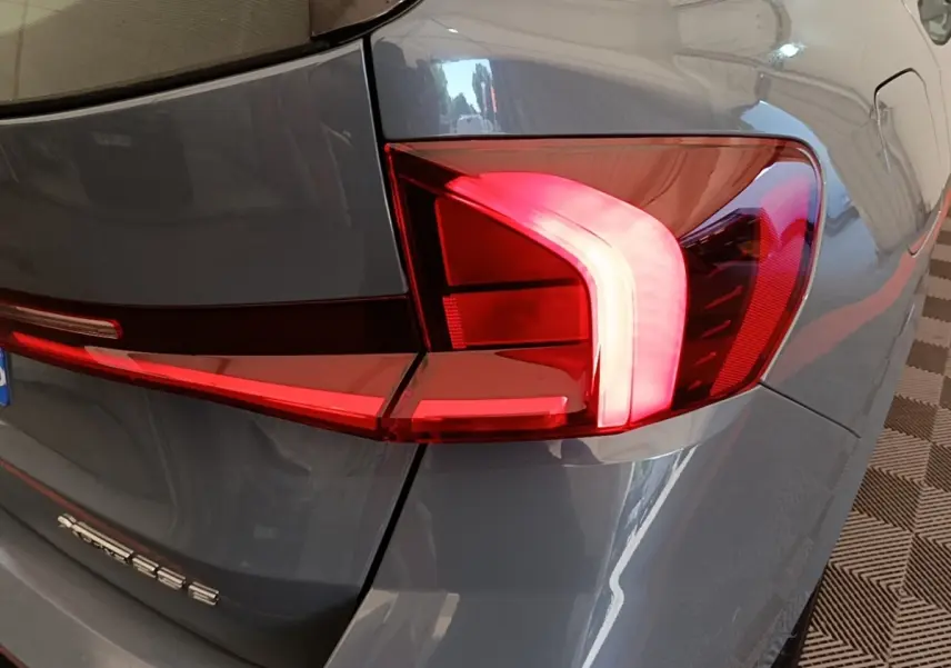 Gros plan sur le feu arrière droit rouge et blanc d’un BMW X1 xDrive25e M Sport gris foncé 2023.