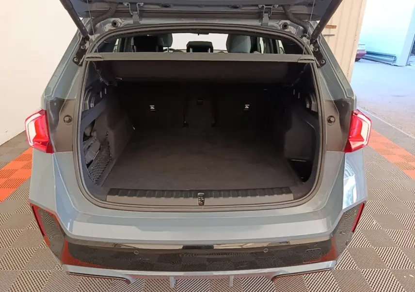 Vue arrière du coffre ouvert d’un BMW X1 xDrive25e M Sport gris foncé, montrant l’espace de chargement vide.