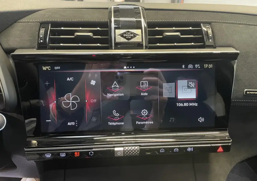 Vue rapprochée de l’écran tactile central noir brillant du DS7 Crossback gris titanium avec commandes climatisation et bouton start/stop.