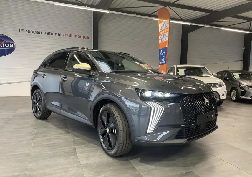 DS7 Crossback gris titanium en 3/4 avant droit, avec calandre noire brillante et feux LED distinctifs en forme de flèche.