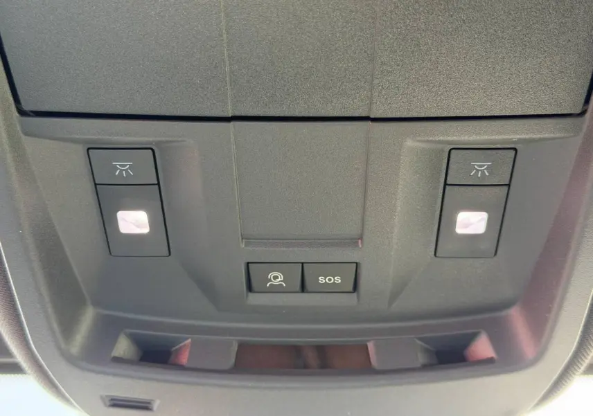 Gros plan sur la console de toit noire du Peugeot 3008 avec boutons d'éclairage et SOS visibles.