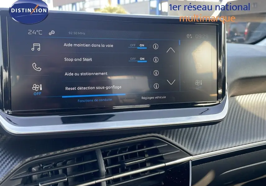 Vue rapprochée de l'écran tactile central du tableau de bord d'une Peugeot 208 blanche, affichant les aides à la conduite.