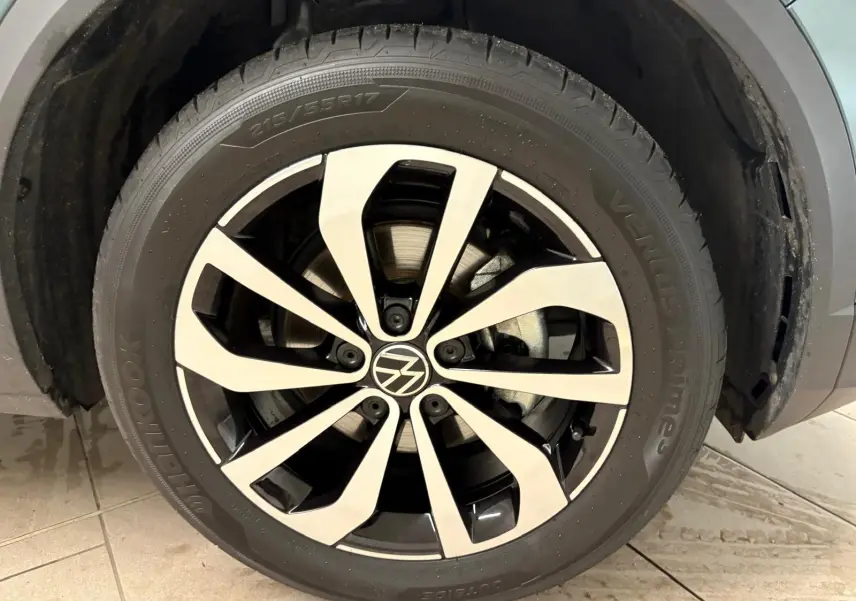 Gros plan sur la jante alliage bicolore du Volkswagen T-Roc 1.5 TSI bleu pétrole, roue avant droite visible.