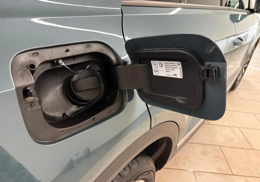 Vue de côté gauche sur le réservoir ouvert du Volkswagen T-Roc bleu pétrole, mettant en valeur la trappe à essence.