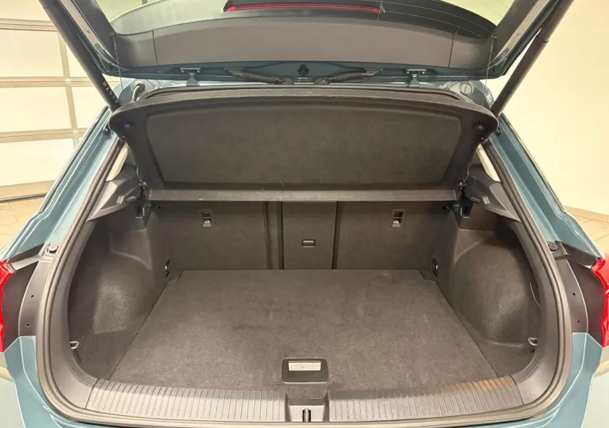 Coffre ouvert vu de l'arrière d'un Volkswagen T-Roc 1.5 TSI bleu pétrole, montrant l'espace de chargement vide.