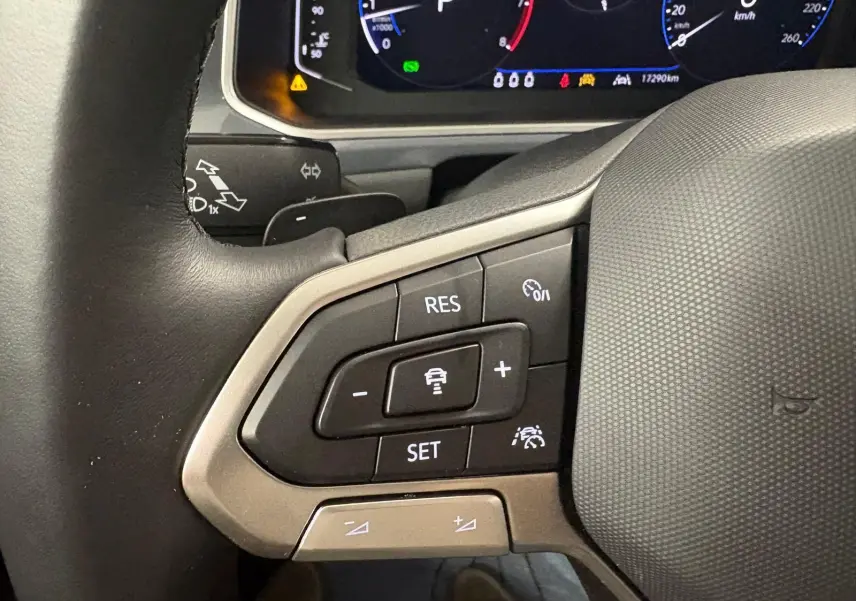 Gros plan sur le volant chauffant du Volkswagen T-Roc 2025, avec commandes intégrées et tableau de bord numérique visible.