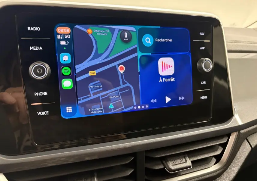 Écran tactile central du Volkswagen T-Roc 2025 affichant navigation et applications, entouré de commandes noires brillantes.