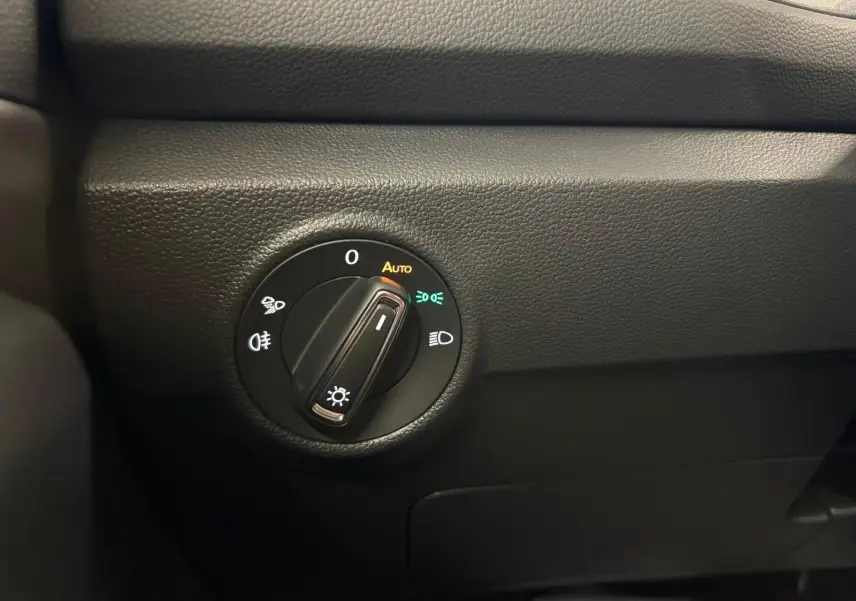 Gros plan sur le bouton de commande des phares du Volkswagen T-Roc 1.5 TSI bleu pétrole, intérieur noir.