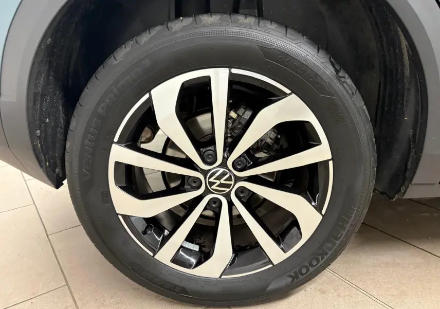 Gros plan sur la jante alliage bicolore du Volkswagen T-Roc bleu pétrole, mettant en valeur le logo VW central.