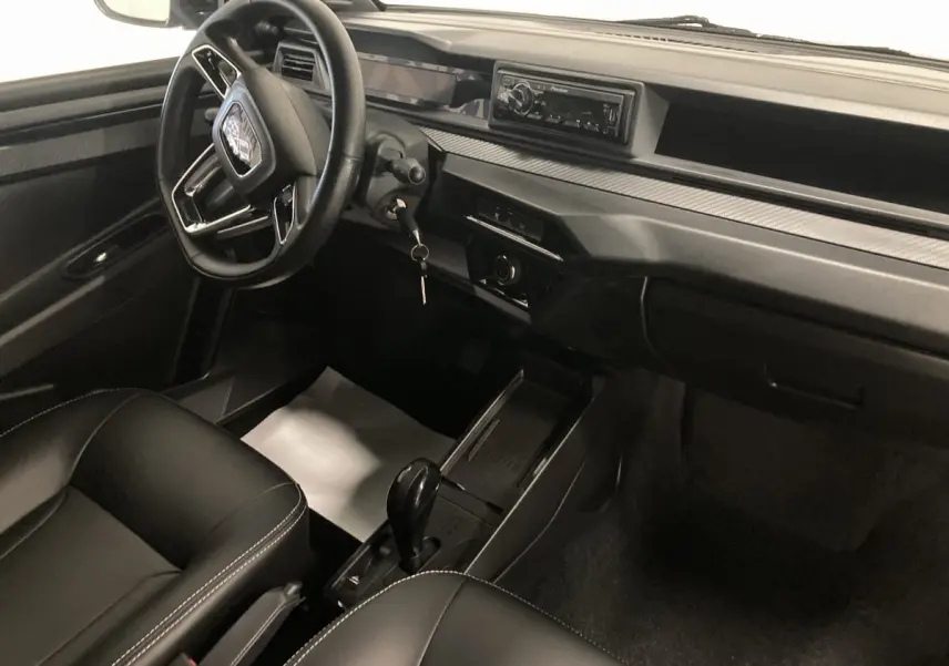 Vue intérieure côté conducteur de la Ligier JS50 0.5 REVO D+ SELECT 2026 noire, avec volant, autoradio Pioneer et boîte auto.