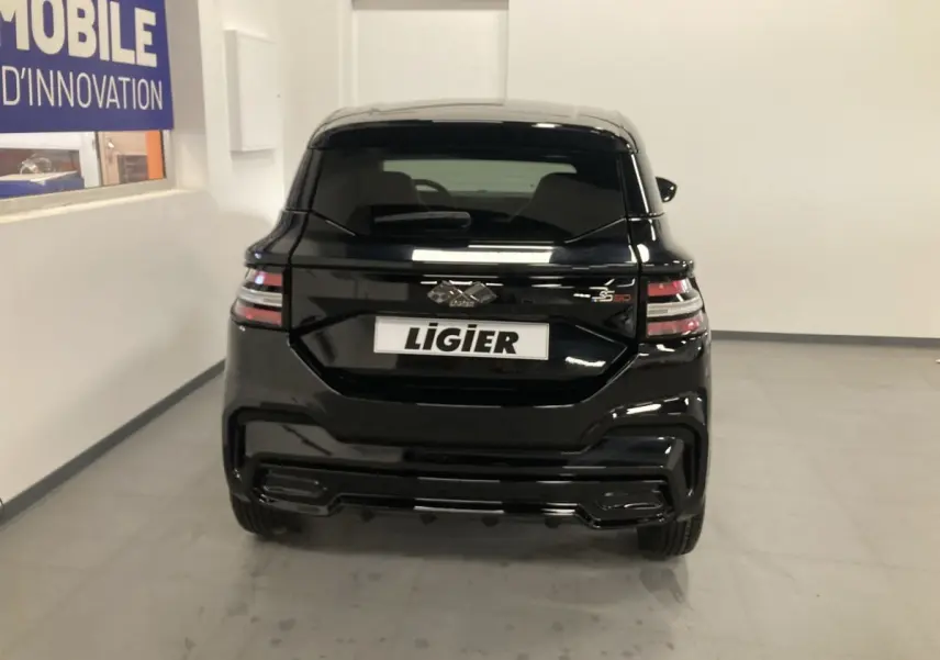 Vue arrière d'une Ligier JS50 noire 2026 avec feux LED et jantes alu noires dans un intérieur blanc.