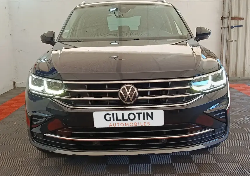 Volkswagen Tiguan noir vue de face avec phares LED allumés et calandre chromée dans un garage.