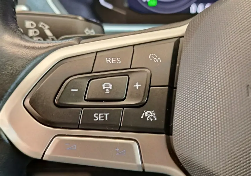 Gros plan sur les commandes du régulateur de vitesse au volant cuir du Volkswagen Tiguan noir 2022.