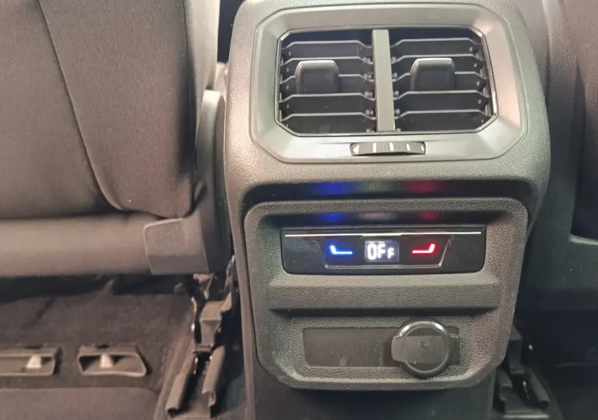 Vue rapprochée de la console arrière noire du Volkswagen Tiguan 2022, avec ventilation et commandes climatisation arrière éteintes.