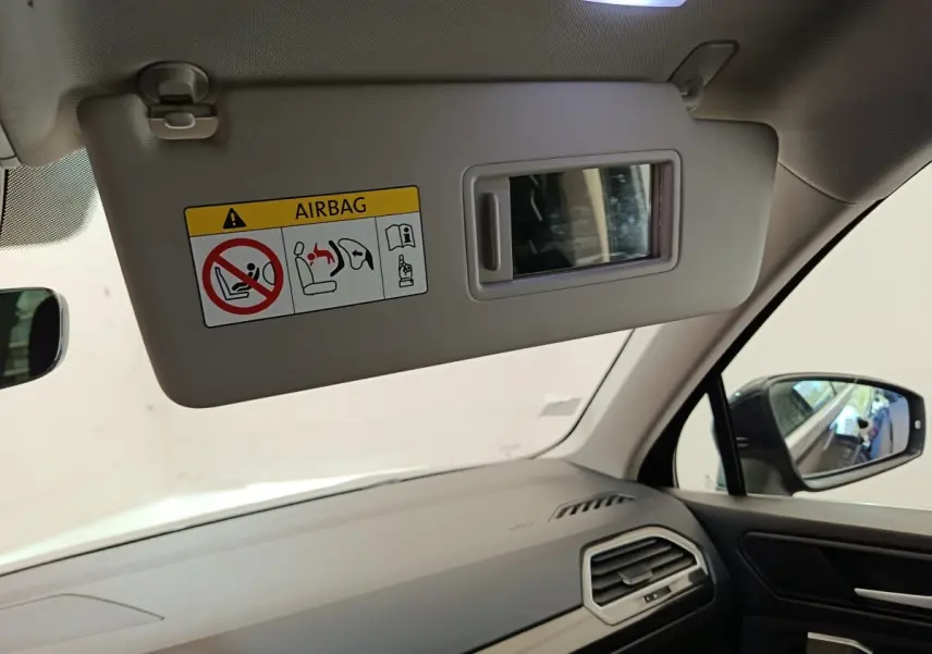 Intérieur du Volkswagen Tiguan 2022 noir, vue côté passager avec pare-soleil abaissé et miroir intégré.