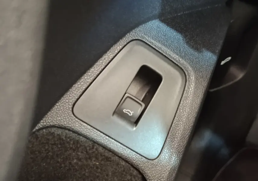Gros plan sur le bouton d'ouverture électrique du coffre dans l'habitacle du Volkswagen Tiguan noir.