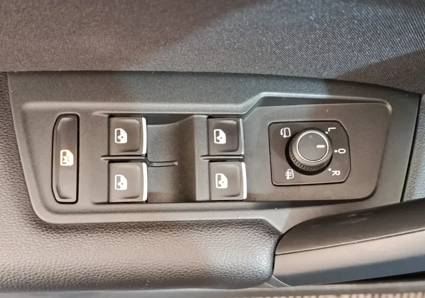 Gros plan sur les commandes de lève-vitres et réglage des rétroviseurs côté conducteur du Volkswagen Tiguan noir 2022.