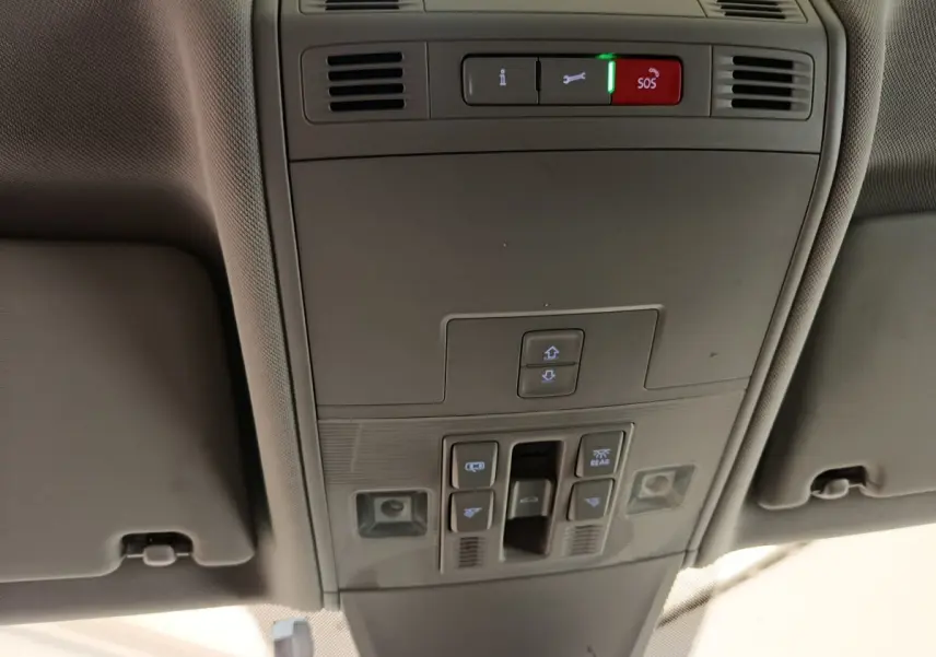 Vue en contre-plongée du panneau de commandes de toit intérieur gris du Volkswagen Tiguan 2022, avec boutons SOS et éclairage.