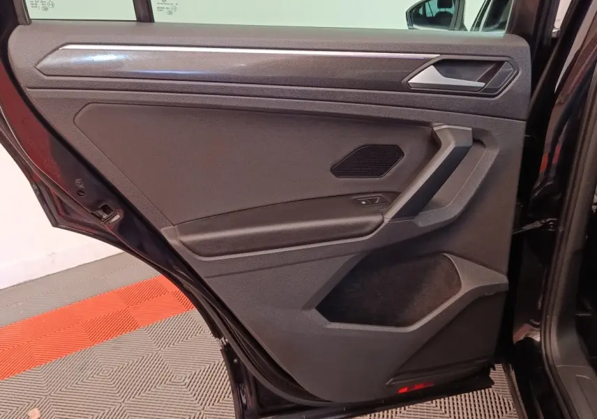 Vue intérieure de la porte arrière gauche noire du Volkswagen Tiguan 2.0 TDI 150 DSG7 Elegance avec habillage sobre.