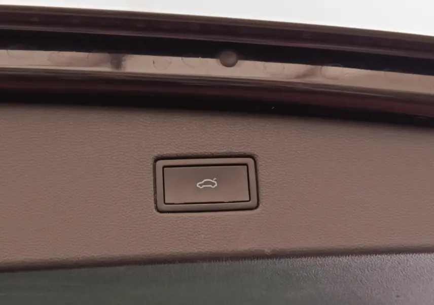 Bouton d'ouverture électrique du coffre sur la garniture intérieure d'un Volkswagen Tiguan noir.
