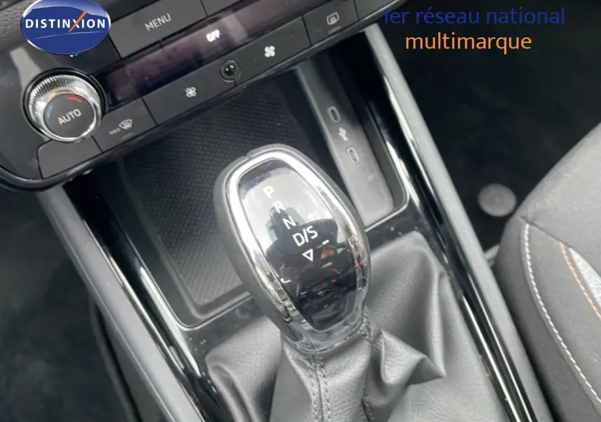 Le levier de vitesse automatique du Skoda Kamiq blanc glacier en gros plan, avec console centrale noire et sièges tissu gris.