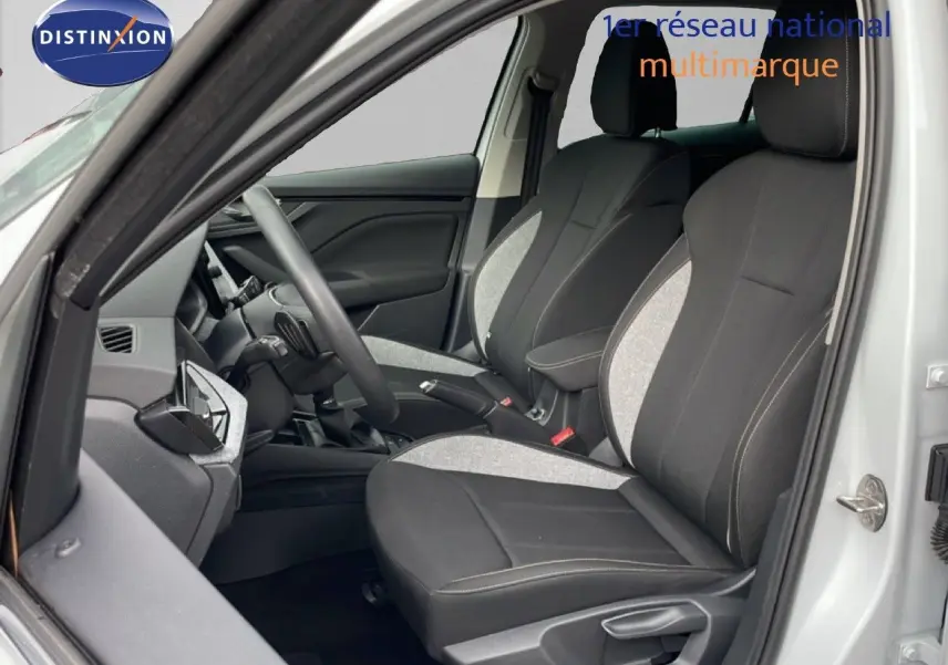 Vue intérieure côté gauche de la Skoda Kamiq 2025 blanc glacier, montrant les sièges avant en tissu bicolore gris et noir.