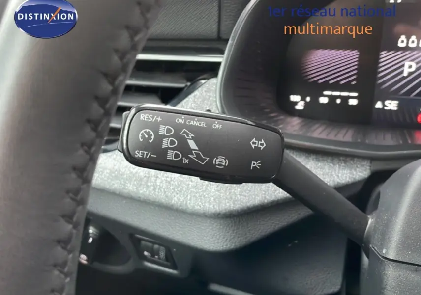 Gros plan sur le commodo gauche du volant d’un Skoda Kamiq 2025, avec tableau de bord numérique en arrière-plan.