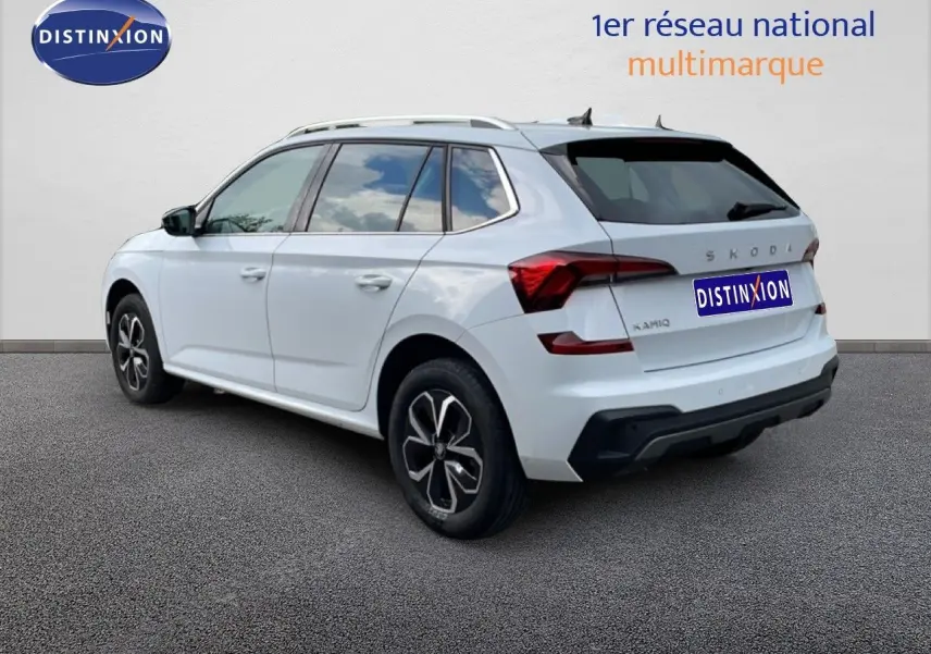 Vue 3/4 arrière droite d'un Skoda Kamiq blanc glacier avec jantes noires et toit ouvrant visible.
