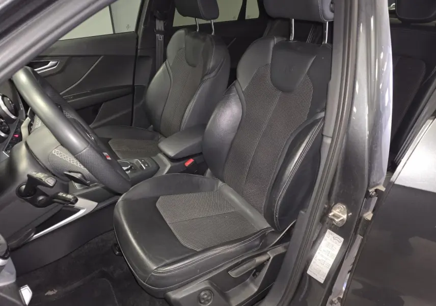 Vue intérieure côté conducteur de l'Audi Q2 gris avec sièges sport cuir/tissu et volant multifonction S line.