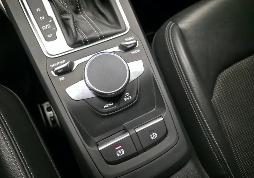 Gros plan sur la console centrale noire de l'Audi Q2 2023 avec molette de commande MMI et levier de vitesse automatique.