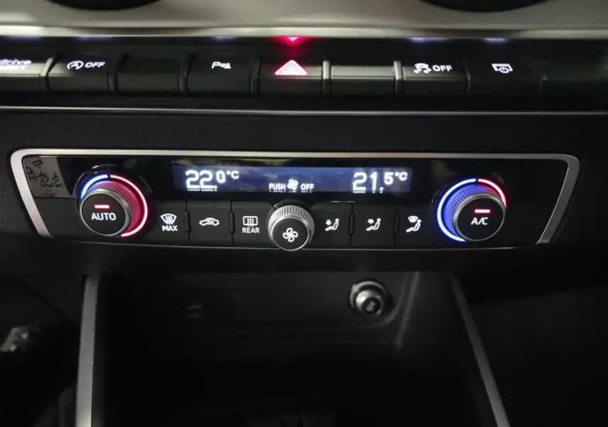 Détail du tableau de bord de l'Audi Q2 2023 avec commandes de climatisation automatique bicolores et affichage digital.