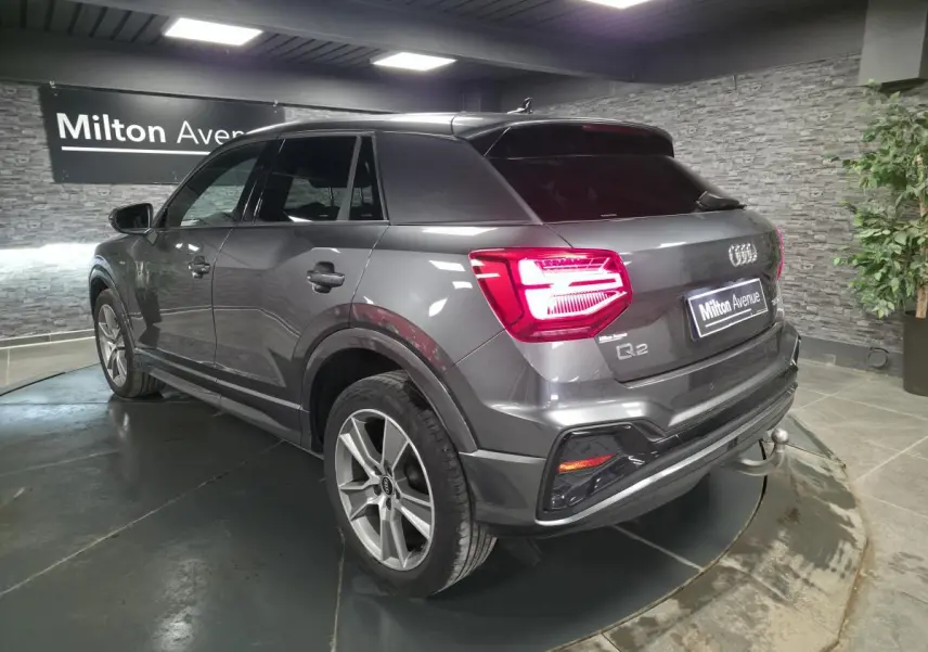 Vue 3/4 arrière droite d'un Audi Q2 gris Daytona avec attelage amovible et jantes 18 pouces en alliage.