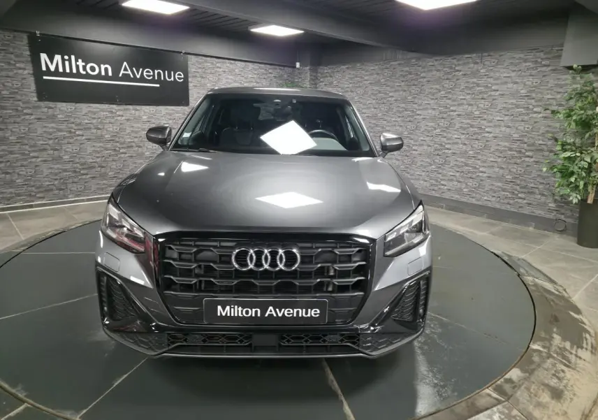 Vue avant d’un Audi Q2 gris Daytona S line Plus 2023 avec calandre noire et logo Audi lumineux.