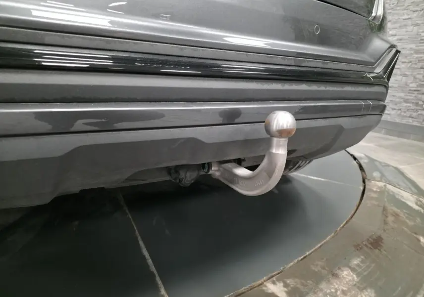 Gros plan sur l'attelage amovible sous le pare-chocs arrière gris nacré d'un Audi Q2 2023 S line Plus.