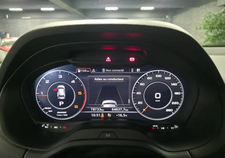 Vue rapprochée du tableau de bord numérique de l'Audi Q2 gris 2023, affichant les compteurs et aides au conducteur.