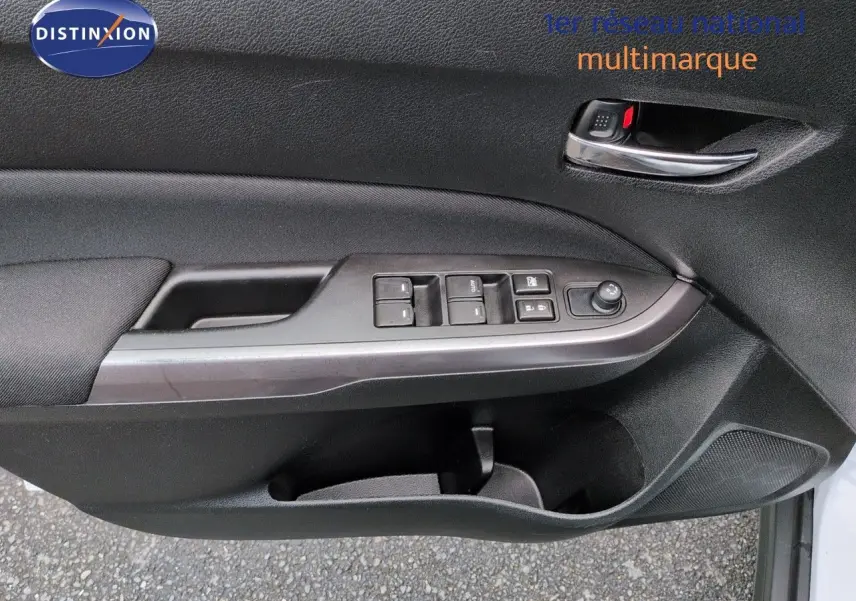 Gros plan sur la porte avant gauche du Suzuki Vitara 1.4 Boosterjet Hybrid, avec commandes électriques et poignée chrome.