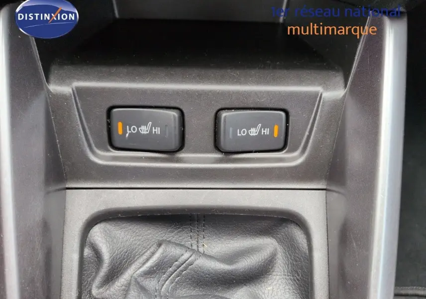 Gros plan sur les commandes des sièges chauffants et soufflet de levier de vitesse en cuir noir dans un Suzuki Vitara gris métallisé.