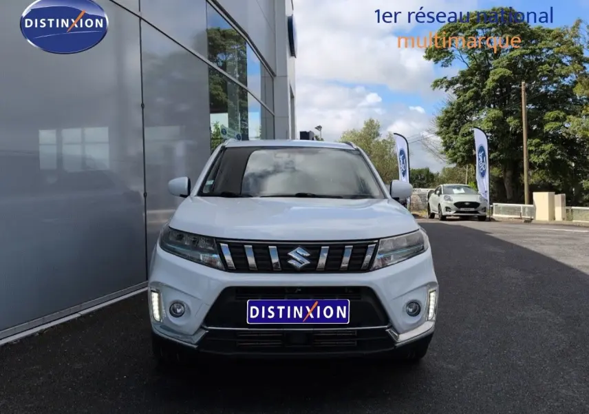 Vue frontale d'un Suzuki Vitara Galactic Gray métallisé avec calandre chromée et feux LED allumés.