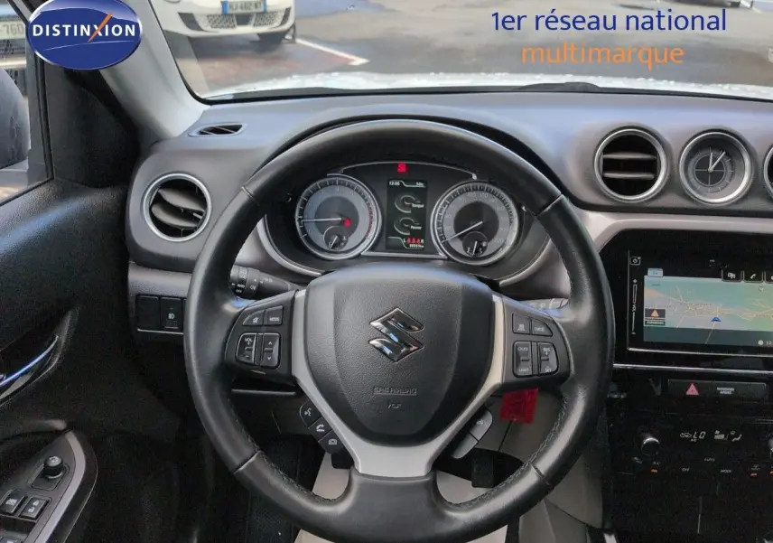 Vue intérieure centrée sur le volant cuir multifonction du Suzuki Vitara 2021 avec tableau de bord et écran tactile visible.