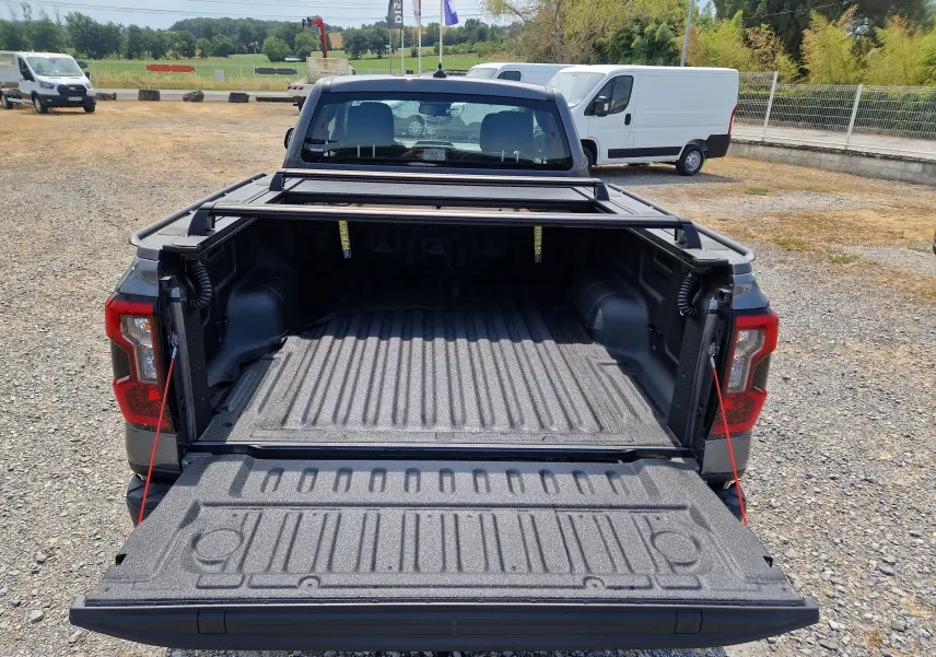 Vue arrière du Ford Ranger Super Cabine gris carbone avec plateau ouvert et rideau rigide coulissant visible.