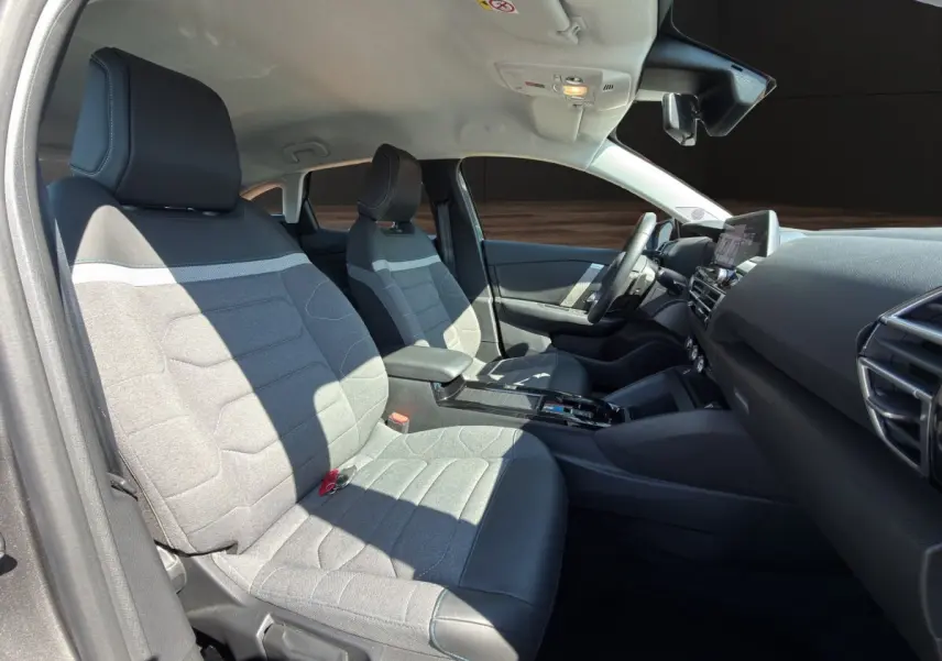 Vue intérieure côté gauche de la Citroën C4 2023, sièges tissu gris et cuir noir, tableau de bord moderne avec écran tactile.