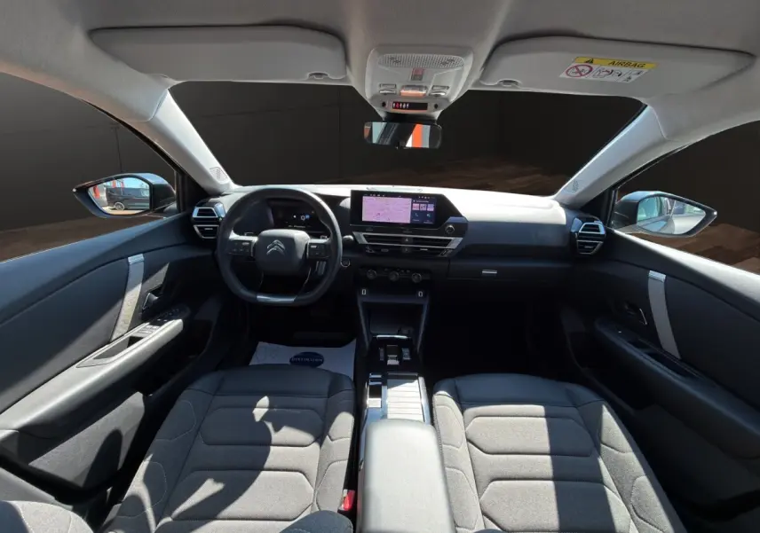 Vue intérieure avant de la Citroën C4 2023 gris foncé, volant cuir multifonctions et écran tactile central visible.