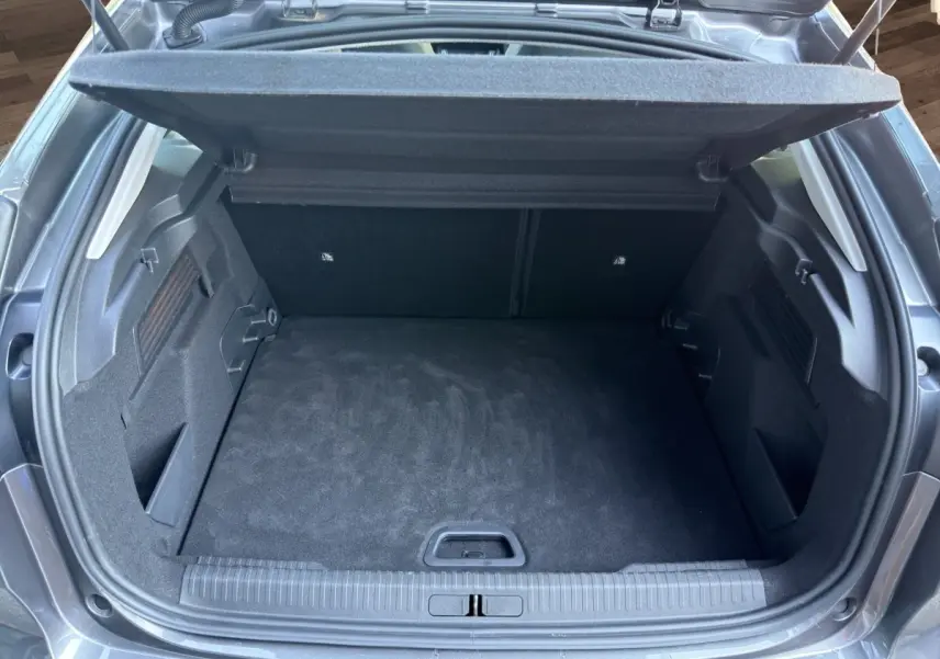 Coffre ouvert vu de l'arrière d'une Citroën C4 gris foncé 2023, espace de chargement propre et spacieux.